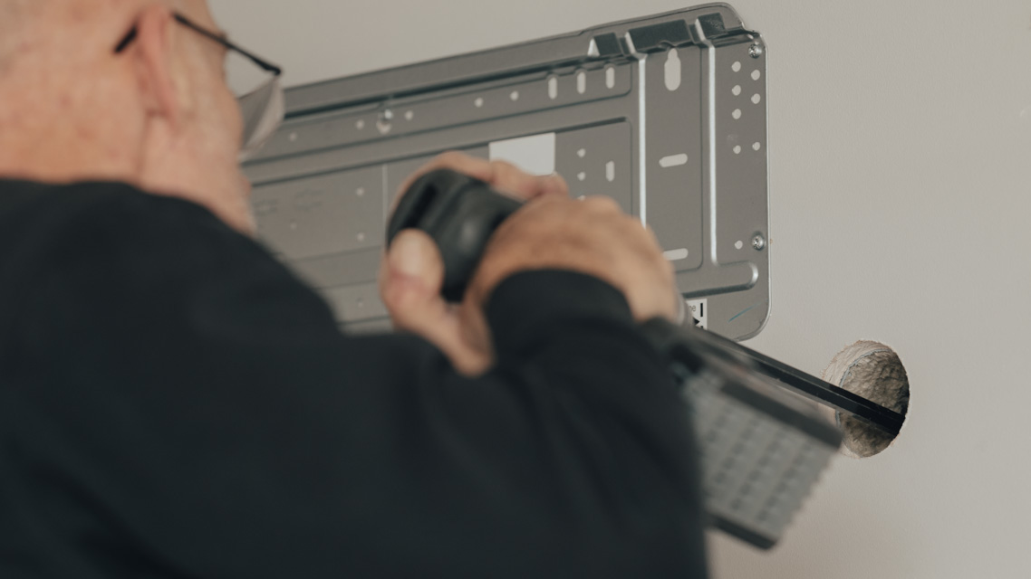 Installatør som tar hull i en vegg